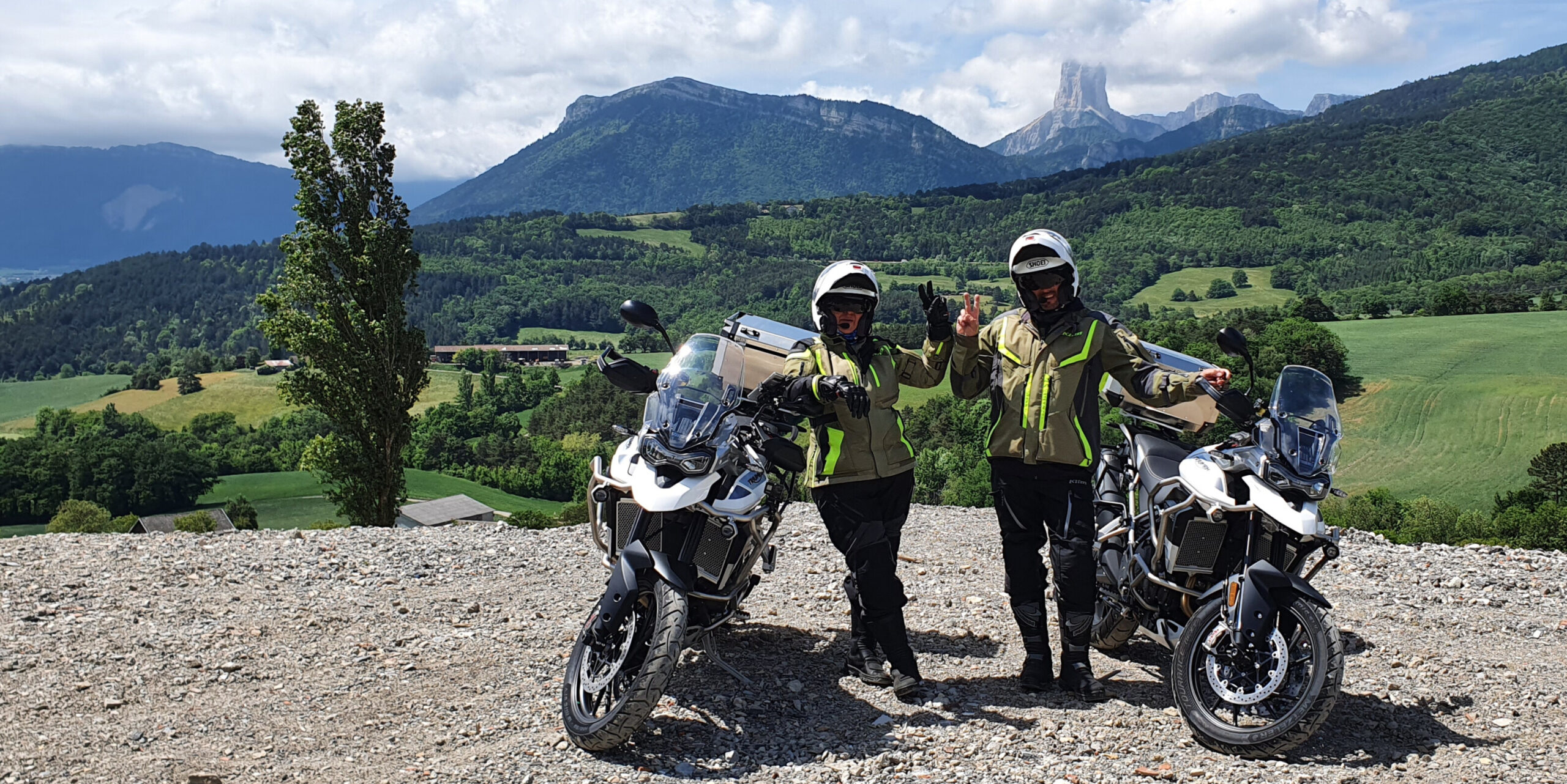 Deux motards accoudés sur leurs motos Triumph Tiger 900 GT Pro devant le Mont Aiguille dans le Vercors en France.
