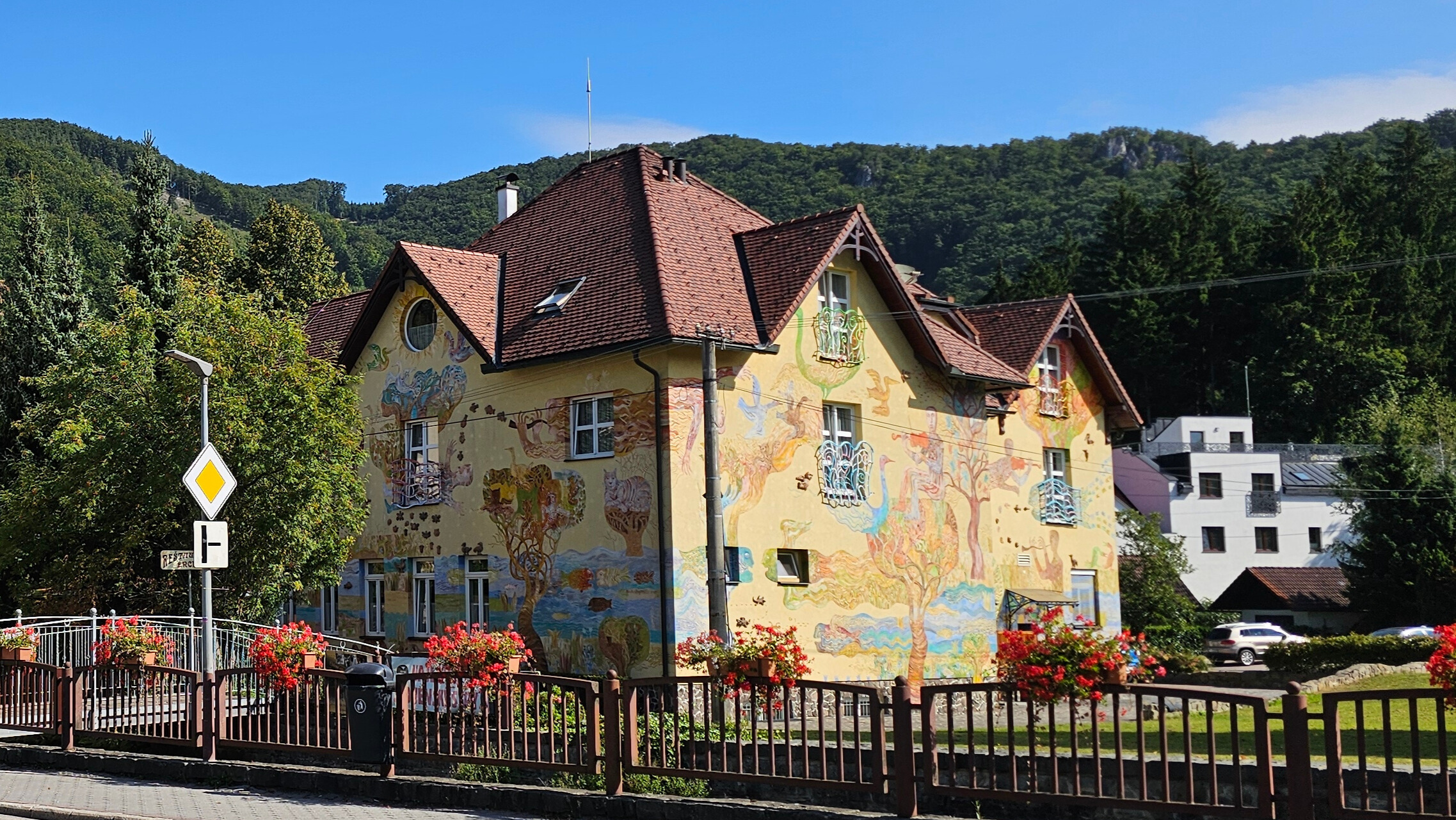Photo d’une maison slovaque joliment décorée, prise à proximité du parc Aphrodite, entourée de verdure et de fleurs.
