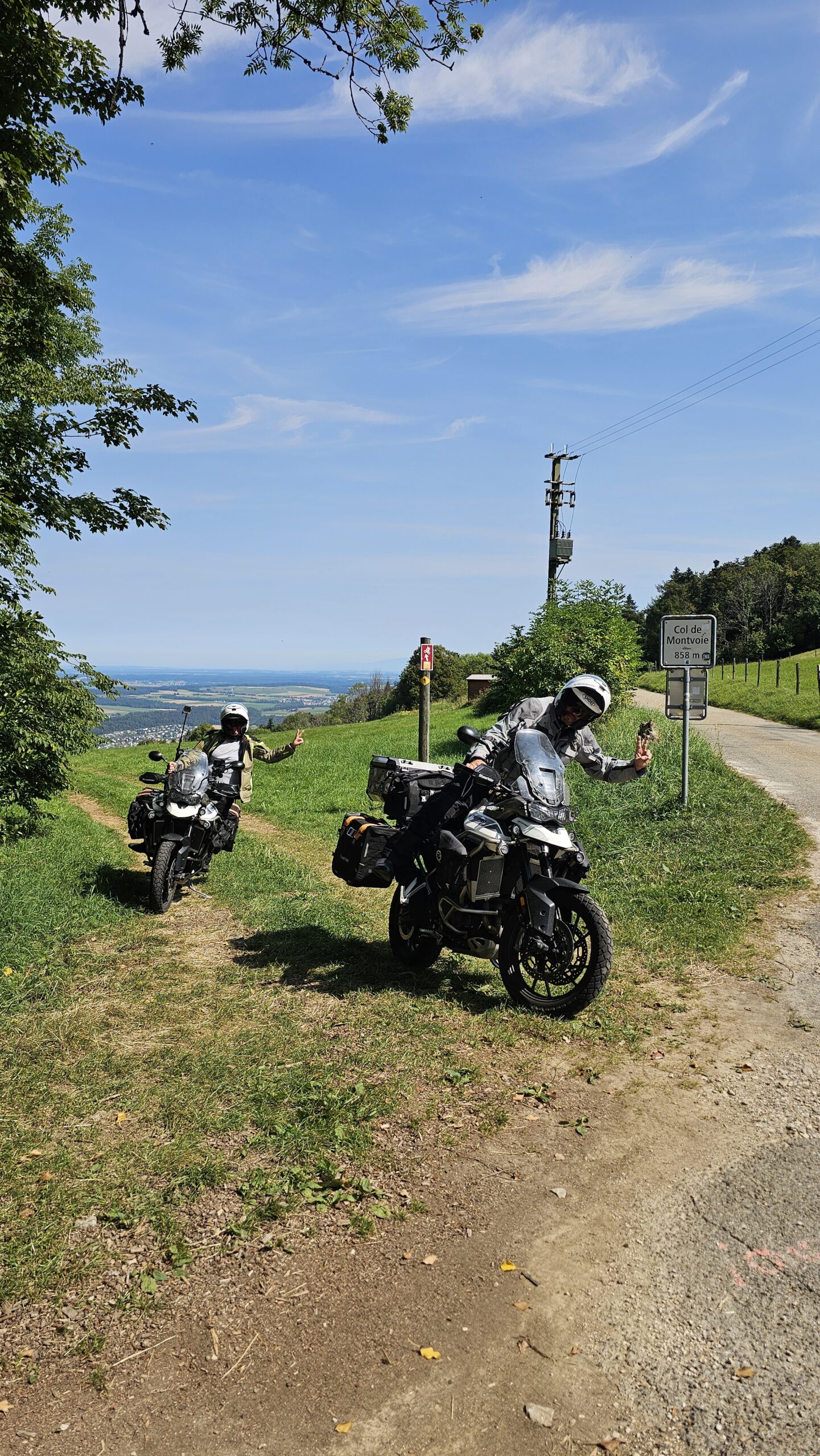 Nos motos sur un chemin offroad au col de Montvoie, à la frontière entre la Suisse et la France, près du panneau marquant le passage.