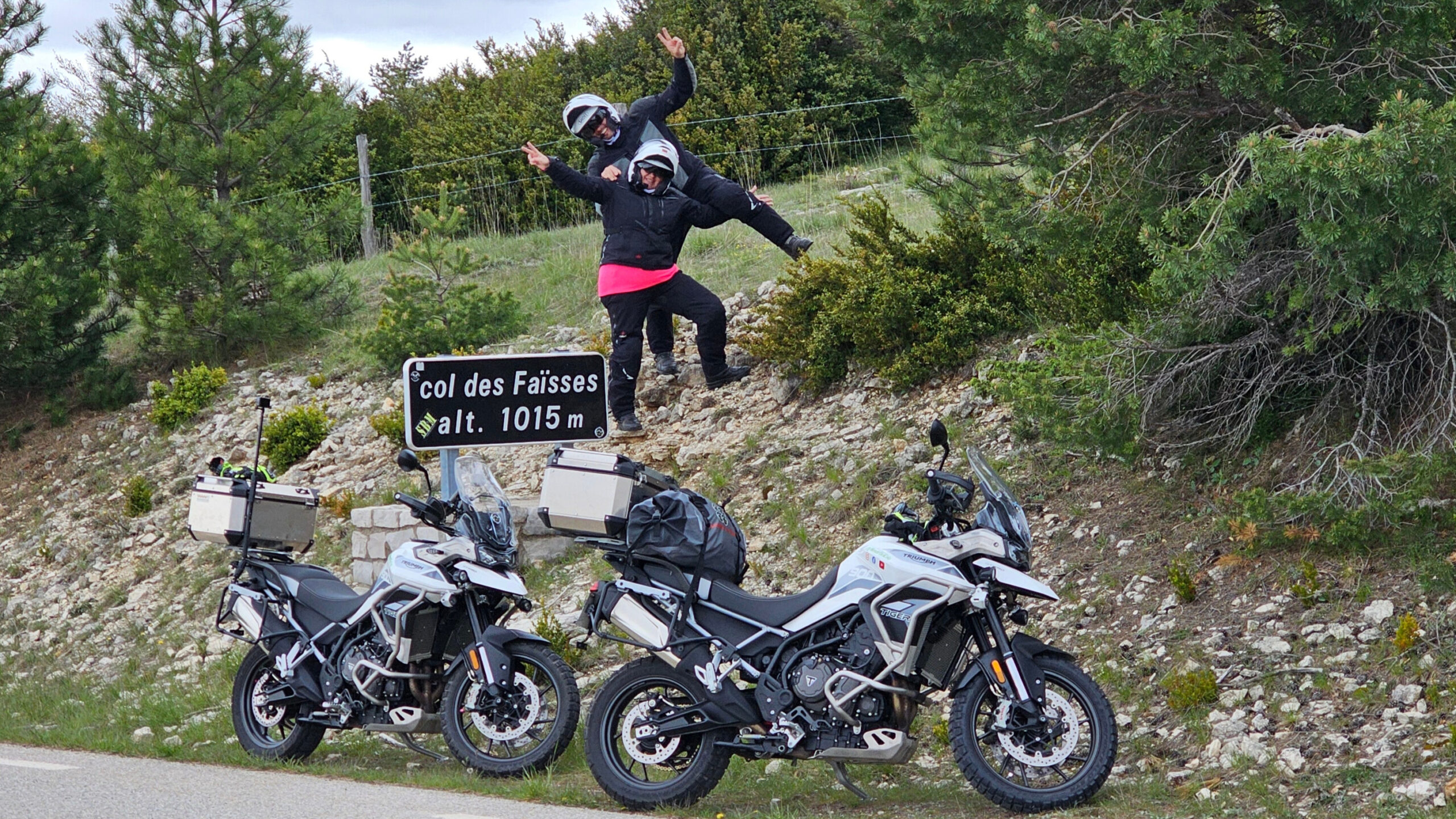 Deux motos garées en contrebas du panneau routier indiquant le col des Faïsses et son altitude, vues depuis le dessus