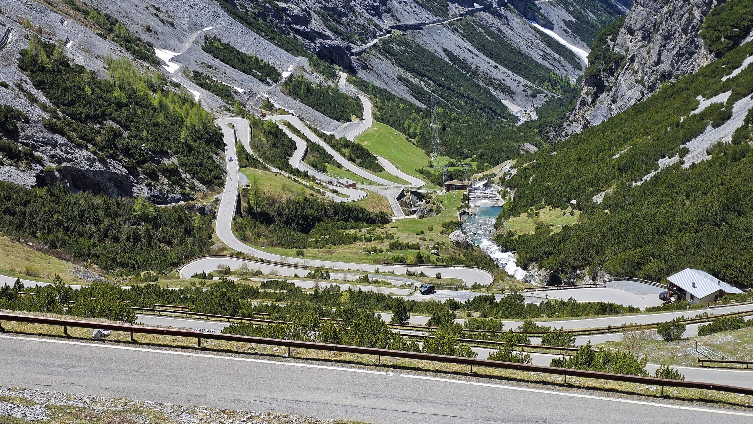 Route sinueuse du versant Bormio avec une cascade en arrière-plan.
