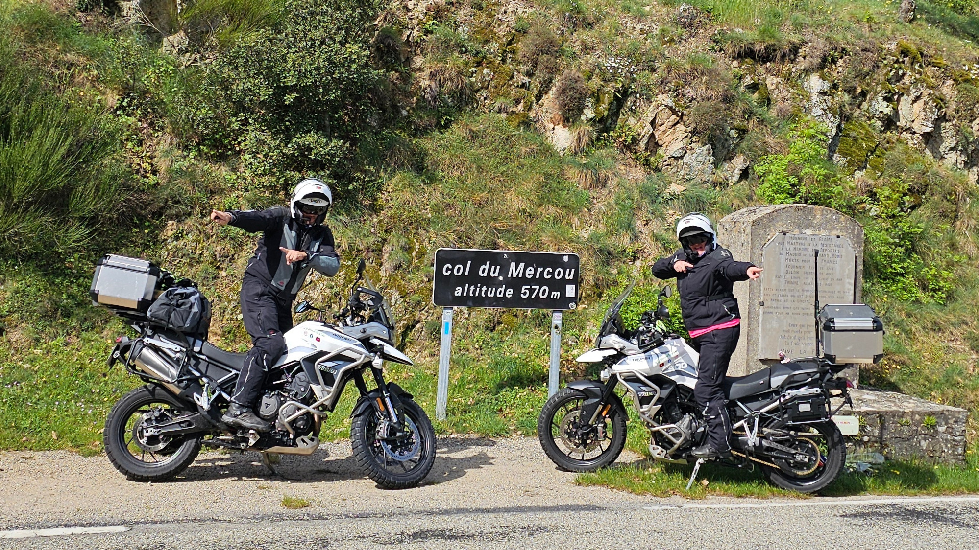 Gros plan sur le panneau routier du Col du Mercou arborant des autocollants de voyageurs, marquant l'arrivée sur la ligne de crête.