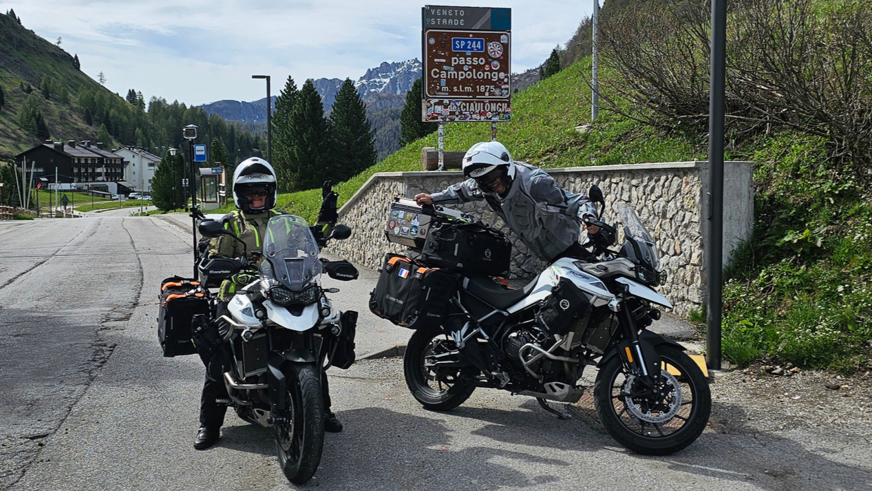 Motards avec sacoches Lone Rider devant le panneau du Passo Campolongo et perche GoPro dans les Dolomites.