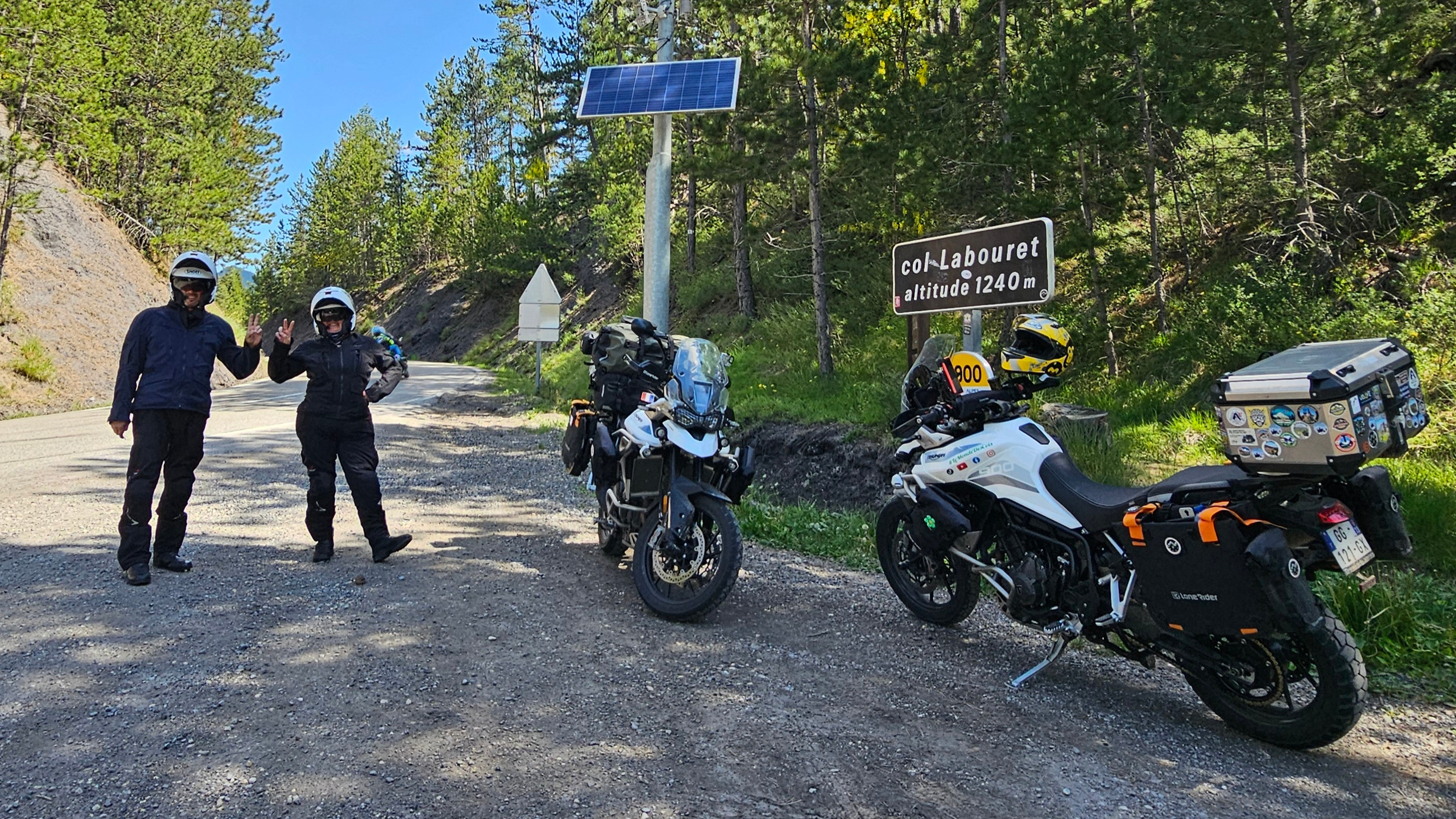 Motard tout sourire faisant le signe de la main au milieu de la route du col du Labouret.