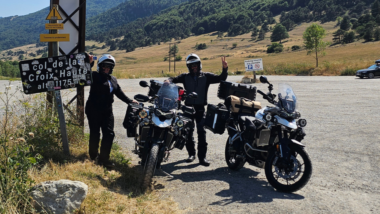 Panneau du col de la Croix Haute avec motards équipés Halvarssons et motos Triumph Tiger 900 GT Pro Lone Rider au sommet.