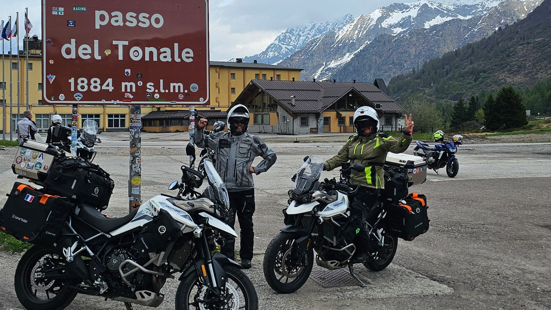 Motards avec sacoches LoneRider posant devant le panneau du Passo del Tonale et son large parking